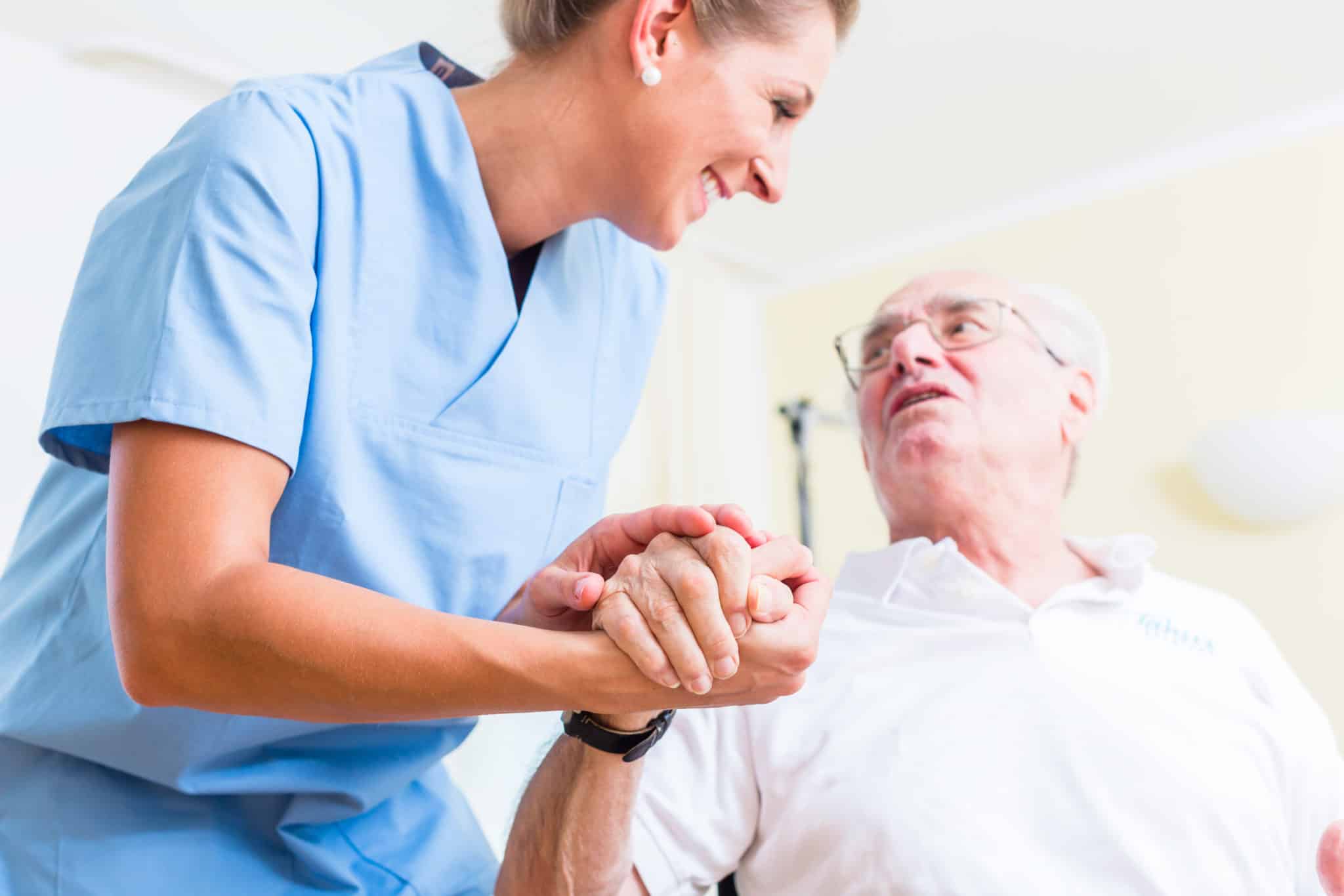 Nurse holding hand of senior man in rest home