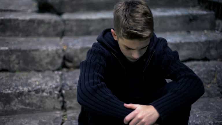 Sad teen sitting on old cracked steps, feeling grief and sorrow, parents loss