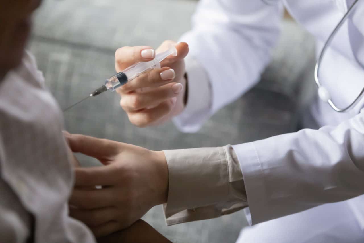 Close up young general practitioner making vaccination treatment injection to older mature male patient at hospital clinic, disease prevention, illness treatment, medical service healthcare concept.
