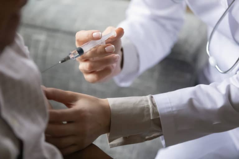 Close up young general practitioner making vaccination treatment injection to older mature male patient at hospital clinic, disease prevention, illness treatment, medical service healthcare concept.