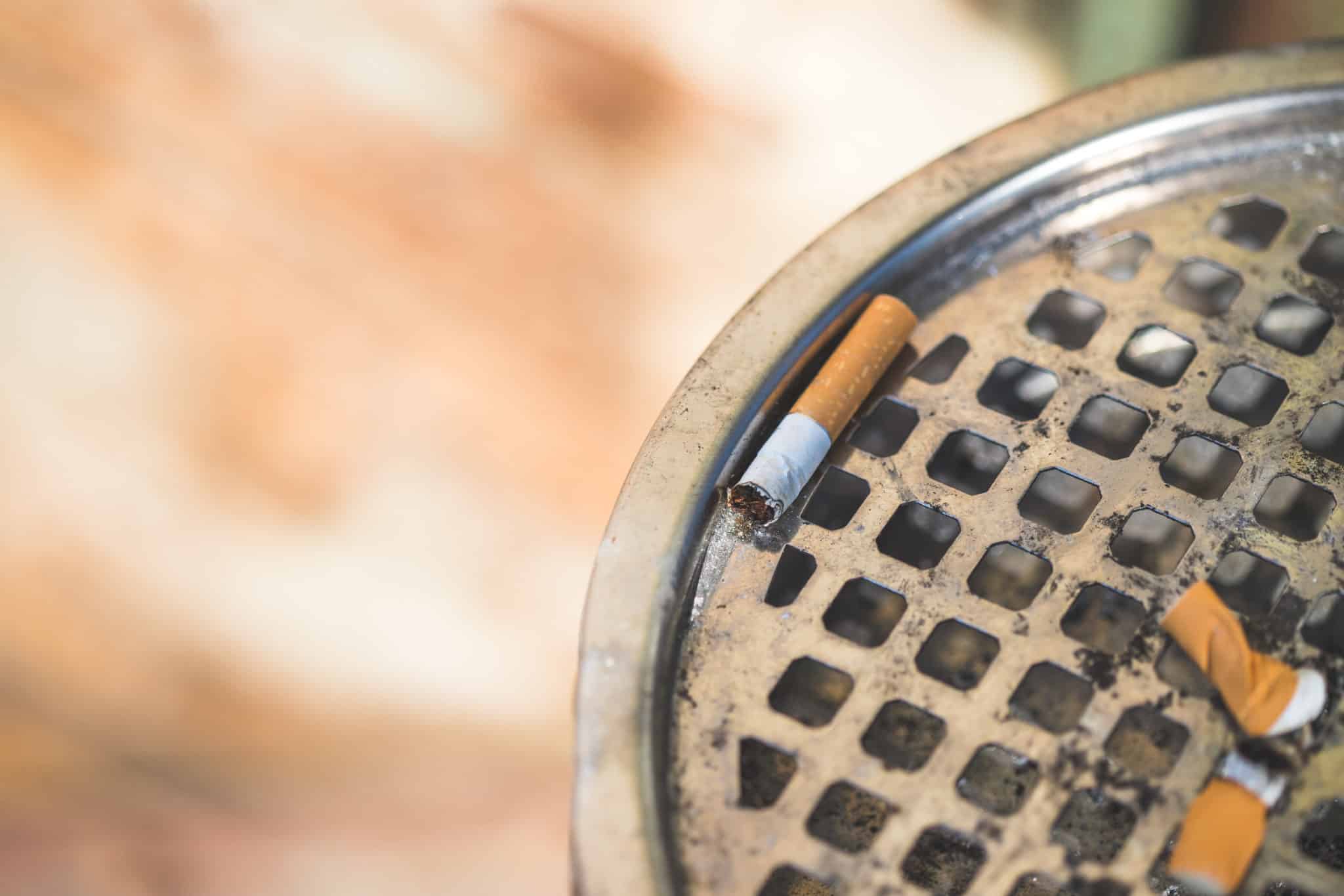 Cigarette lying in public metal ashtray, close up picture